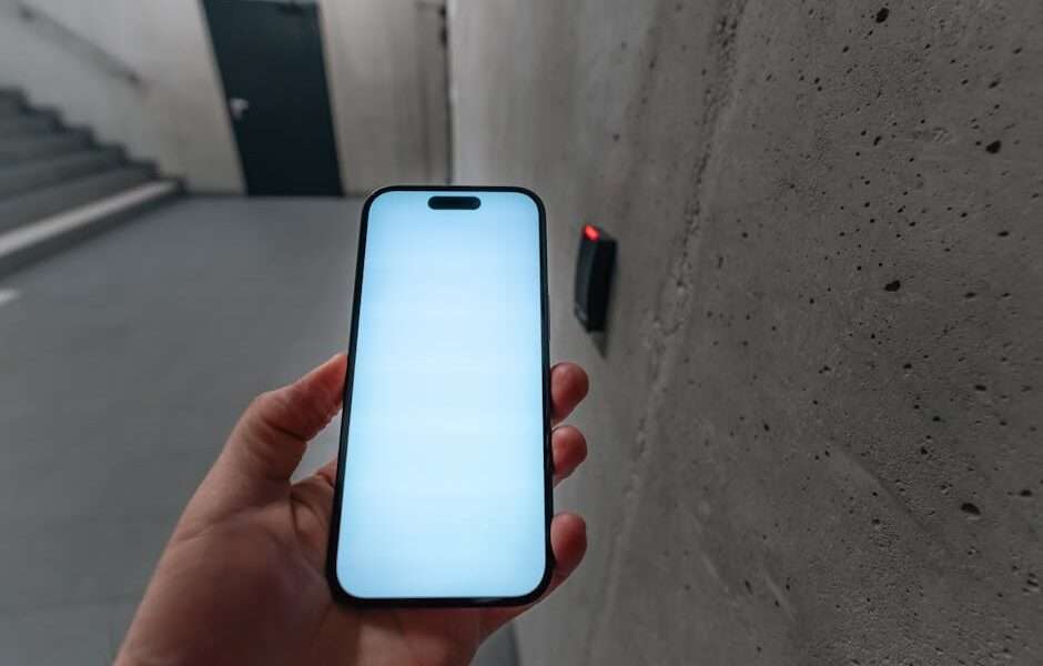Osoba trzymająca smartfon z białym ekranem przed czytnikiem dostępowym.